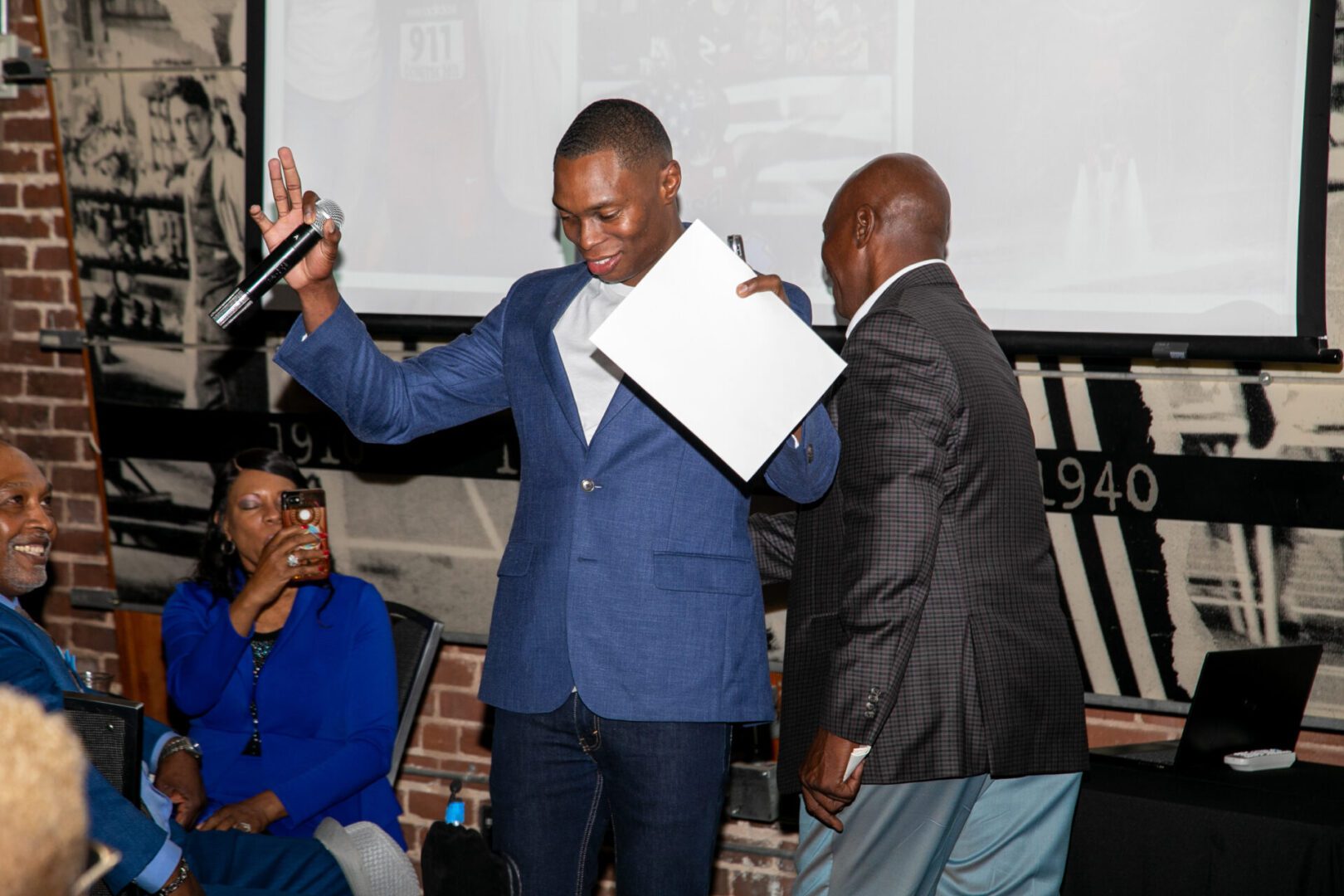 A man holding up papers while standing next to another man.